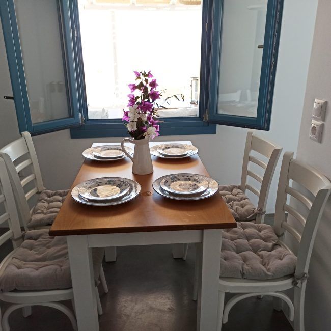 The inner dining room with the low window overlooking the veranda and the endless Aegean