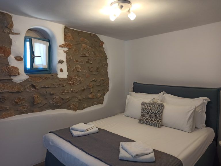 The separate bedroom with the stone wall and the double bed has a low window overlooking the Aegean